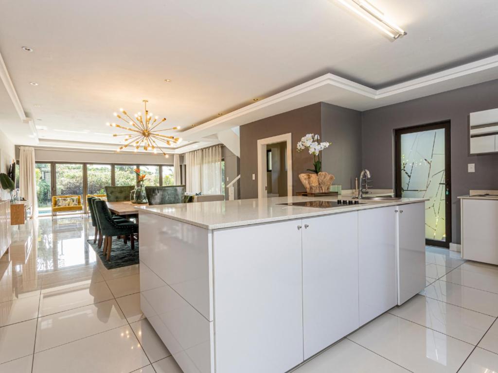 a kitchen with white cabinets and a dining room at Corals 4, Zimbali Estate by Euphoric Leisure in Ballito