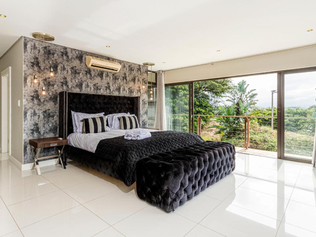 a bedroom with a large bed and a large window at Corals 4, Zimbali Estate by Euphoric Leisure in Ballito