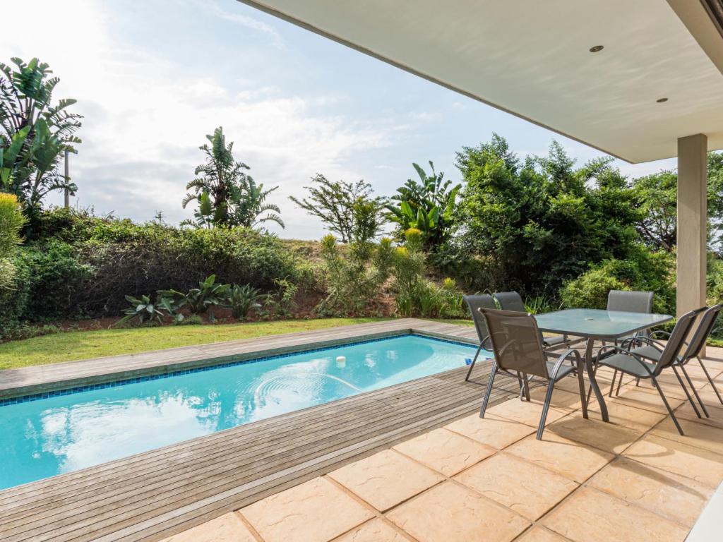 a patio with a table and chairs next to a swimming pool at Corals 4, Zimbali Estate by Euphoric Leisure in Ballito