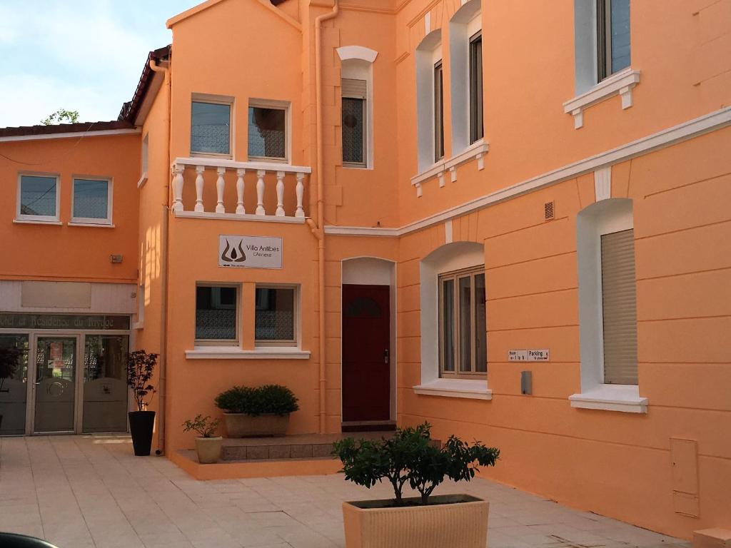 un bâtiment orange avec un arbre devant lui dans l'établissement Hôtel et Appart 'hôtel Chez Gino ETAPLES-Le Touquet, à Étaples