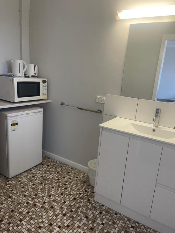 a kitchen with a microwave and a sink at Castle Motel Bairnsdale in Bairnsdale