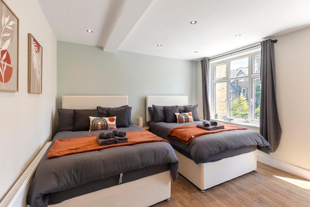 Dos camas en una habitación con ventana. en Kew Garden Suite 2BR Sleeps 9 Near Central London, en Richmond upon Thames