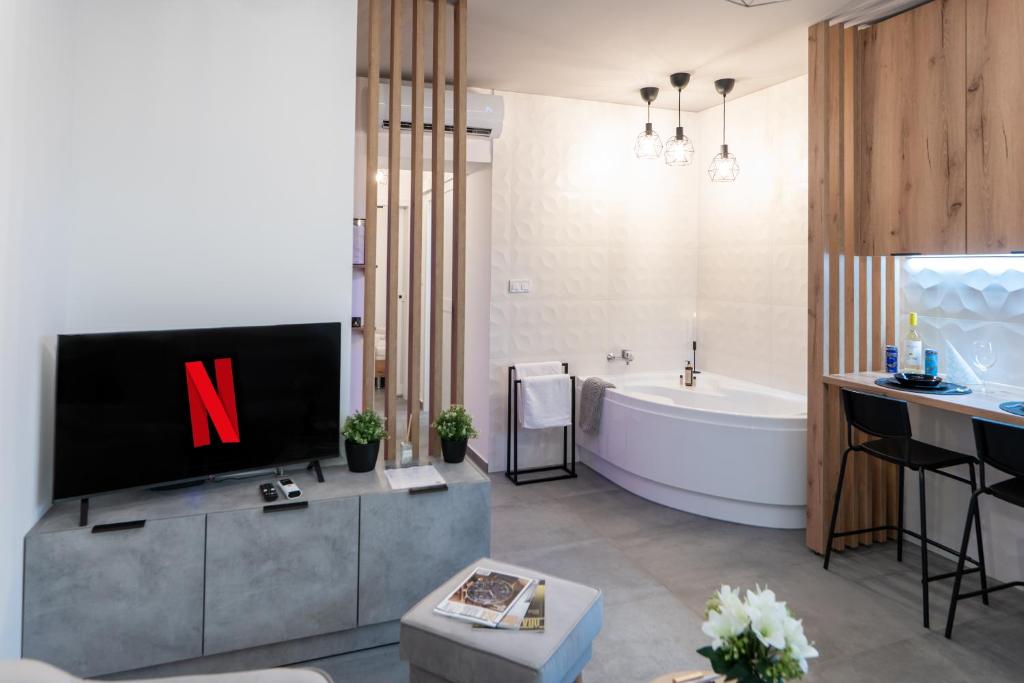 a bathroom with a tv and a tub and a sink at AApartman Wellness in Pécs