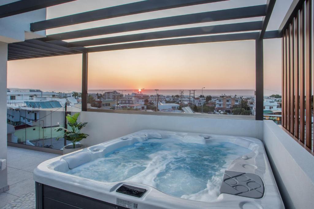 a hot tub on a balcony with a view of the city at Jimmy’s Garden in Faliraki