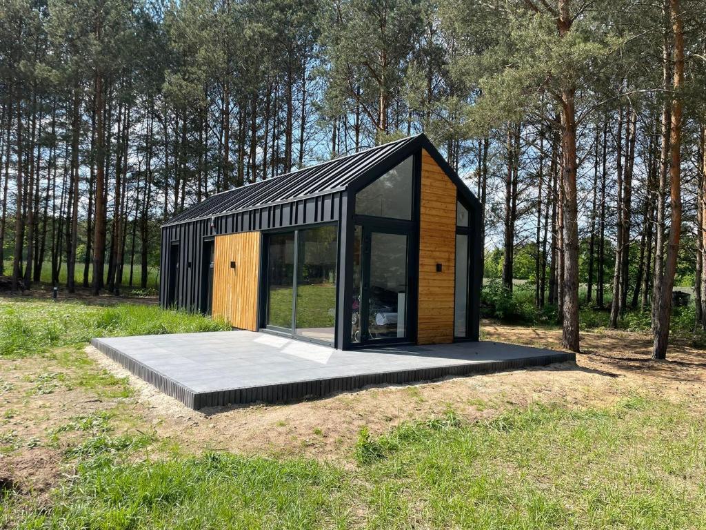 ein schwarzes Holzhaus auf einem Feld mit Bäumen in der Unterkunft EkoRelax & Fun Resort in Dobków