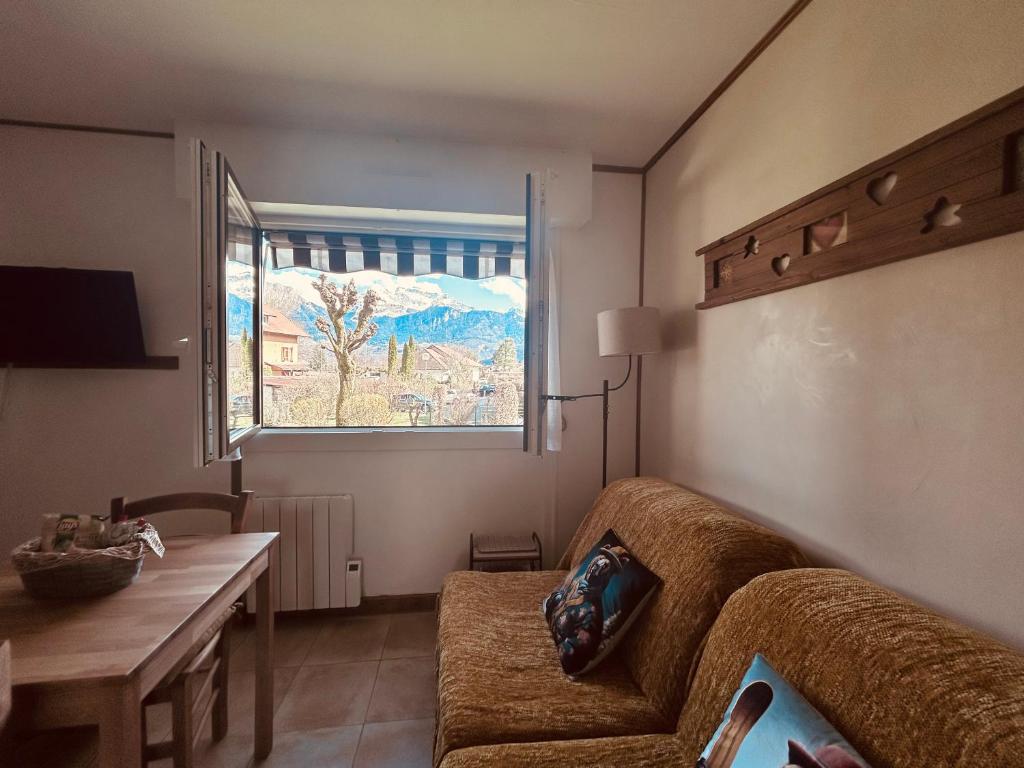 un salon avec un canapé, une table et une fenêtre dans l'établissement À 5 minutes du lac,studio tout confort, parking privé gratuit, lit queen-size, à Saint-Jorioz