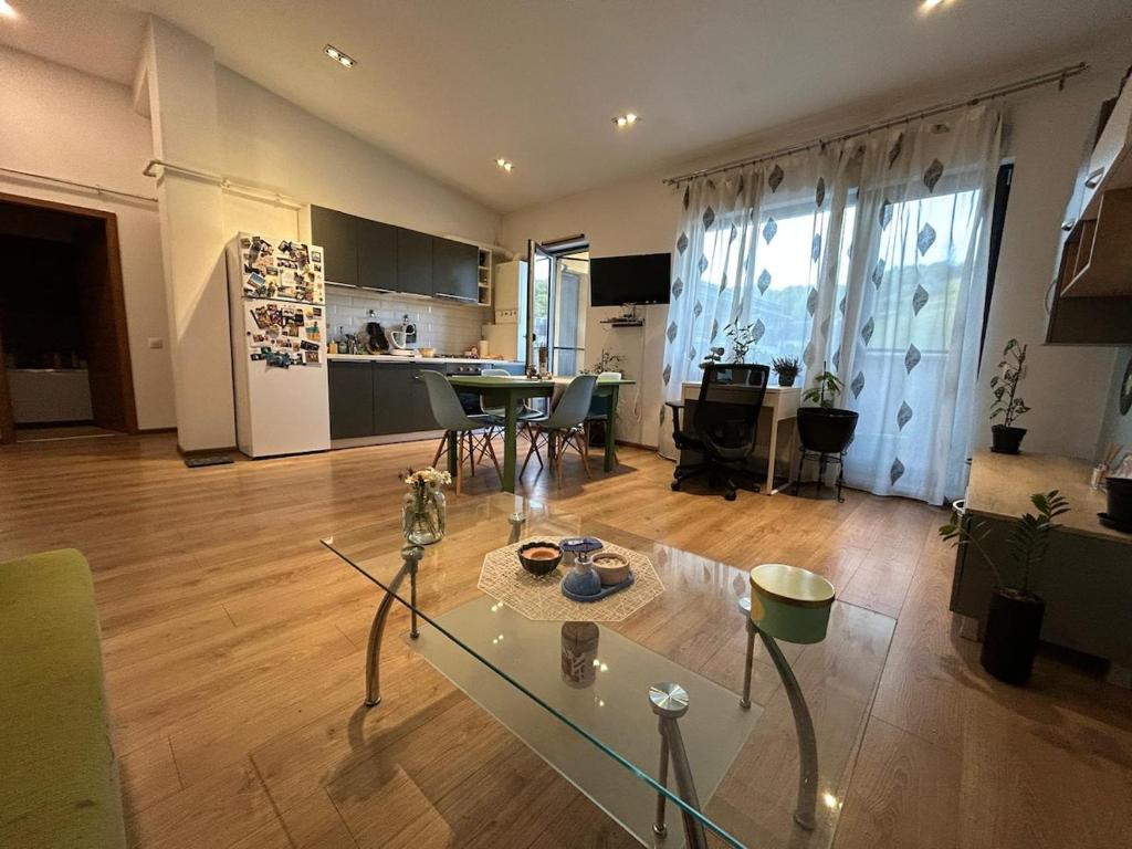 a living room with a glass table and a kitchen at Cozy Gem Cluj meets Nature in Floreşti
