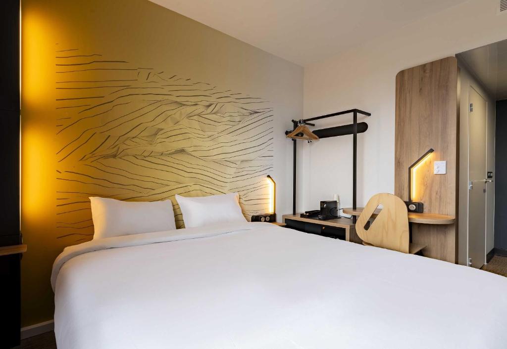 a bedroom with a large white bed and a desk at B&B HOTEL Valenciennes Onnaing 3 étoiles Parc d Activités de la Vallée de l Escaut in Onnaing