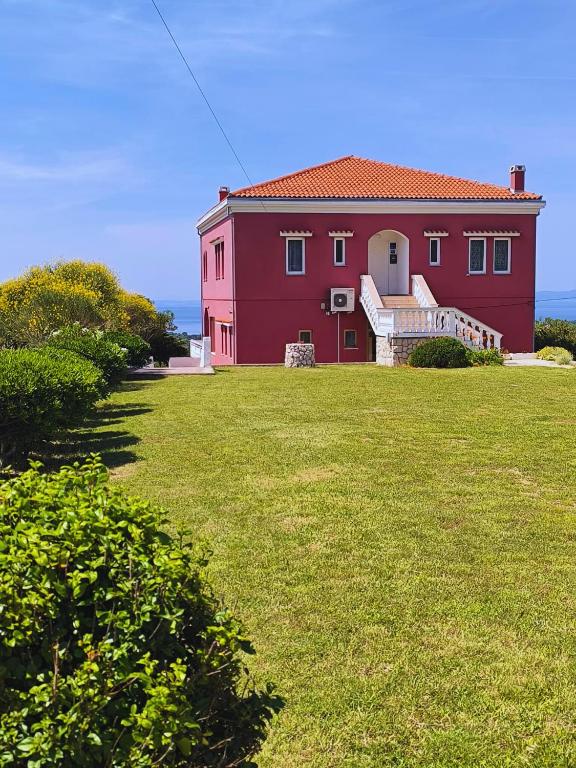 a red house with a grassy yard in front of it at Panoramic View Apartment Leonardo in Rab