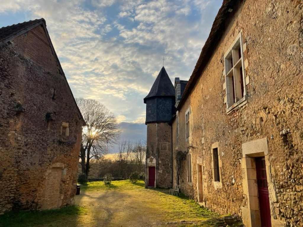 un vieux bâtiment avec une tour au milieu d'une rue dans l'établissement Domaine de Fontenay, à Fontenay-sur-Vègre