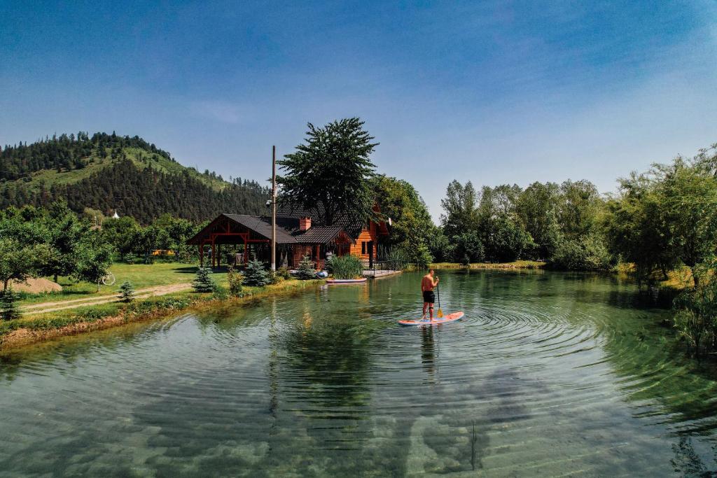 a man is standing on a surfboard in the water at Moonlake Chalet in Găineşti