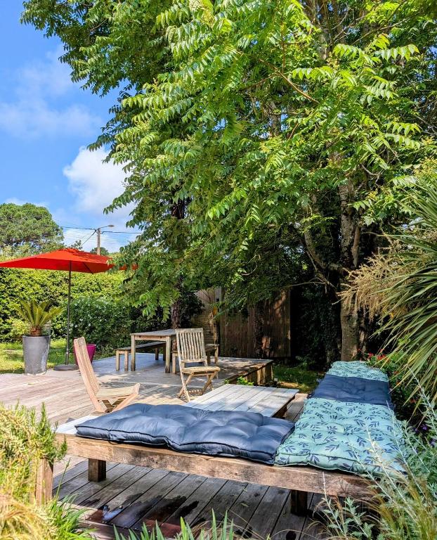 un lit sur une terrasse en bois avec une table et un parasol dans l'établissement La villa Brévinoise - Elégante maison pour 6 personnes, à Saint-Brévin-les-Pins