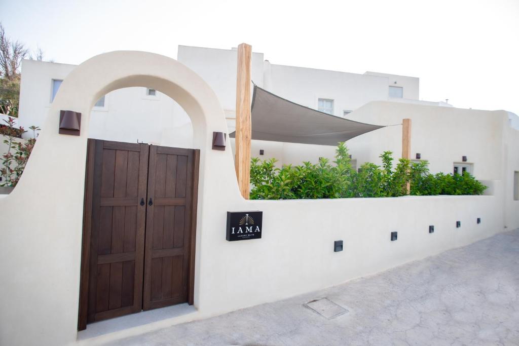 un edificio con una porta e una finestra con piante di Iama Luxury Suite Santorini a Imerovigli