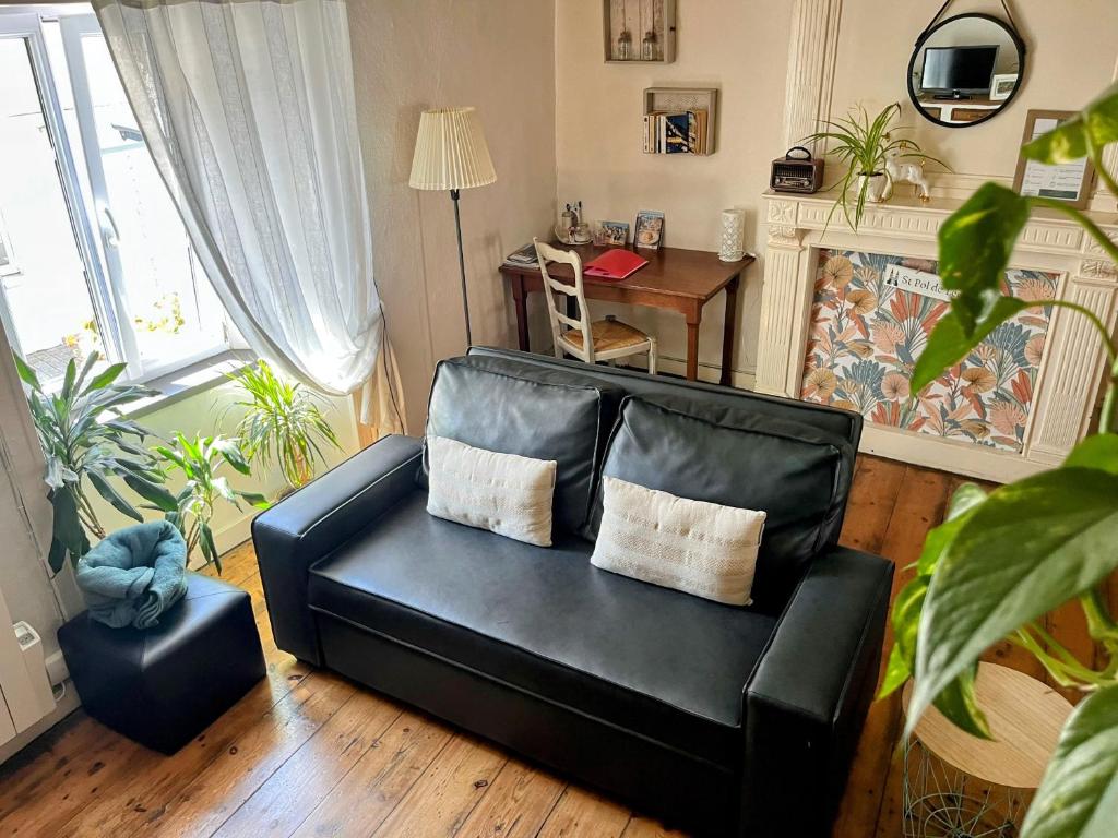 un canapé en cuir noir dans un salon avec une table dans l'établissement Duplex au lin, à Saint-Pol-de-Léon