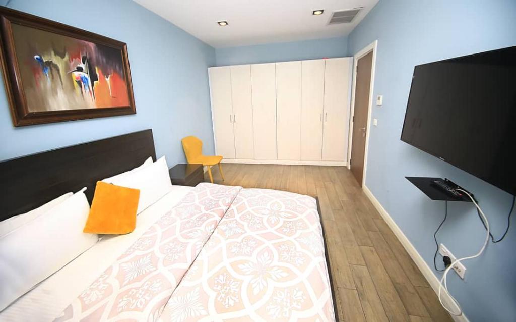 a bedroom with a large bed and a flat screen tv at Pearl of Love Apartment in Accra