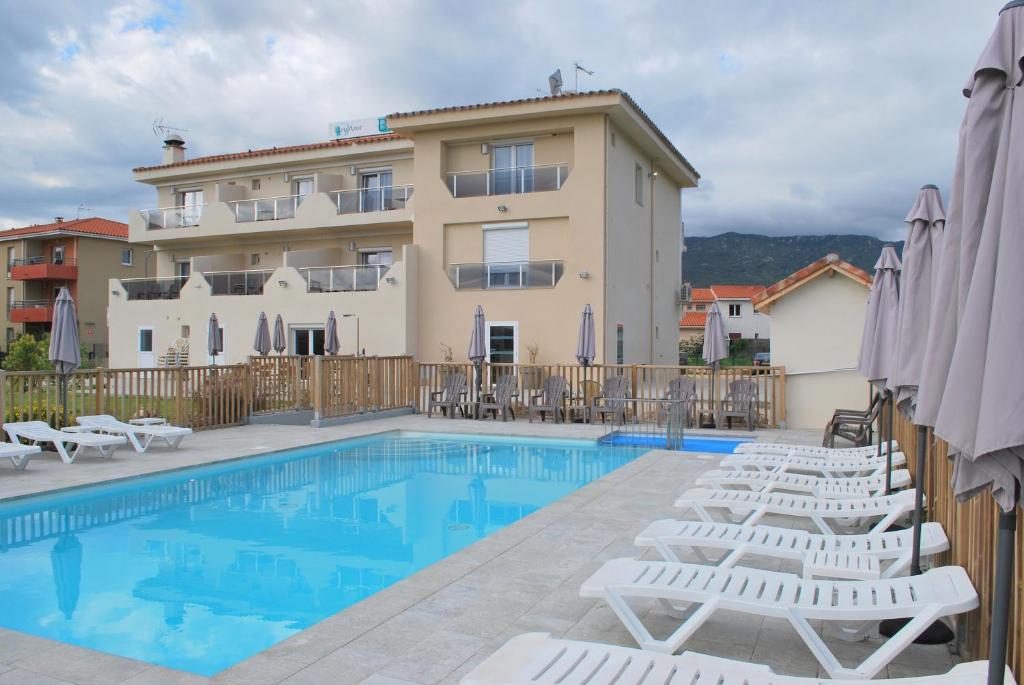 un hotel con una piscina con sillas y un edificio en Hotel Bleu Azur, en Argelès-sur-Mer