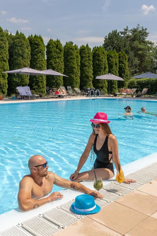 a man and a woman sitting in a swimming pool at Hotel Atlantis in Brno