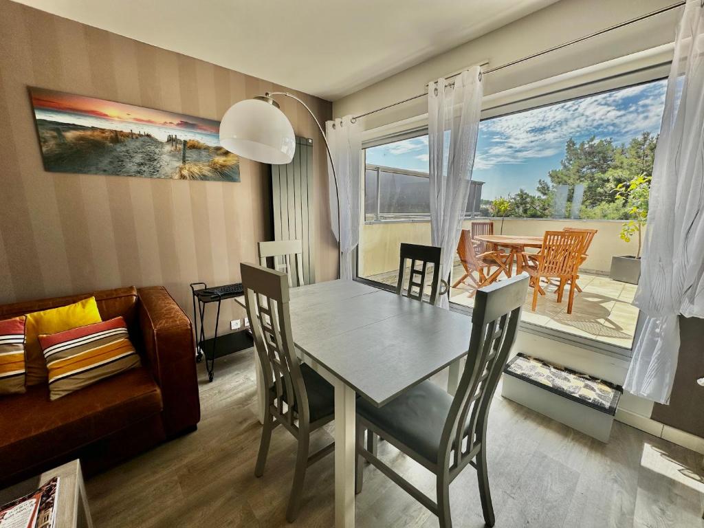un salon avec une table et des chaises et une salle à manger dans l'établissement La mouette rieuse, terrasse, vue mer, accès plage, à Bernières-sur-Mer