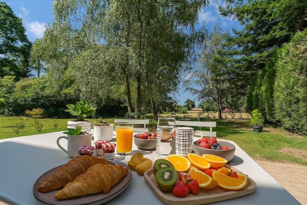 un tavolo con una colazione a base di frutta, croissant e succo di frutta di Séjour nature dans un charmant cottage a Saint-Aubin-dʼAubigné
