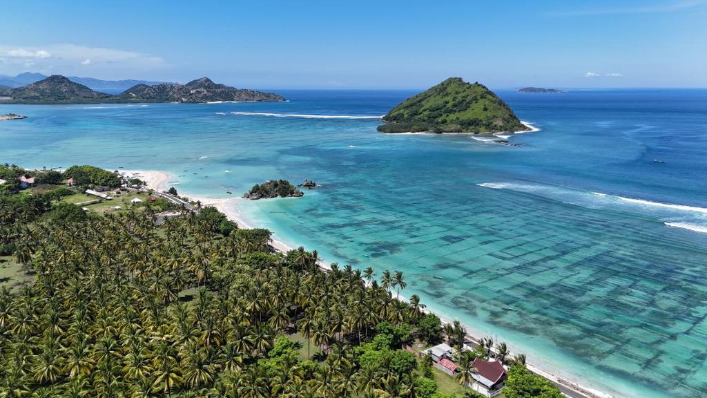 an aerial view of a beach with palm trees and the ocean at Rumah Mana Beach House in Pulau Sarang