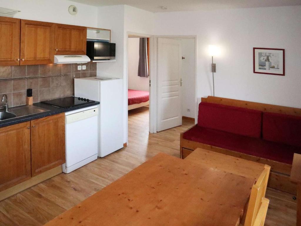 - une cuisine avec un canapé rouge dans une chambre dans l'établissement Les Orres 1800: Appart 3 pièces, Piscine, WiFi, Animaux admis - FR-1-322-431, aux Orres