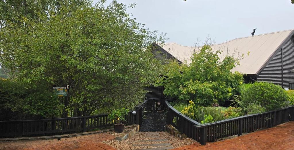 a black fence in front of a house with trees at Khumbula Lodge in Underberg
