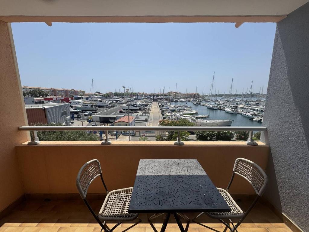 d'une table et de chaises sur un balcon avec un port. dans l'établissement Appartement 4 Personnes avec Piscine et Parking au Cap d'Agde - FR-1-749-28, au Cap d'Agde