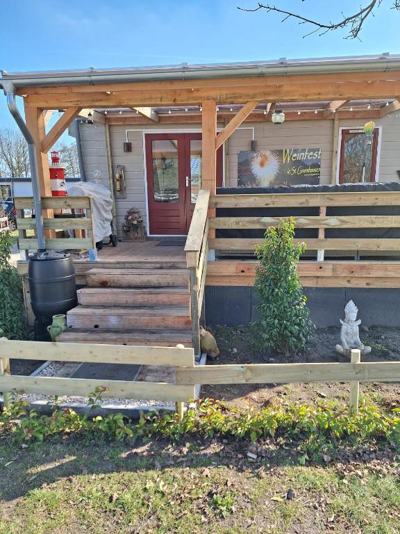 a house with a wooden porch and a wooden stairs at Cosy 1 bedroom chalet near the woods in Anloo