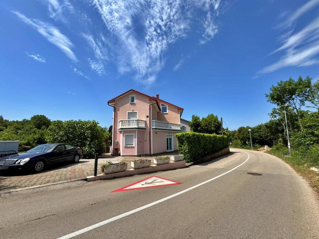 a small pink house on the side of a road at Apartments Vodopija in Soline