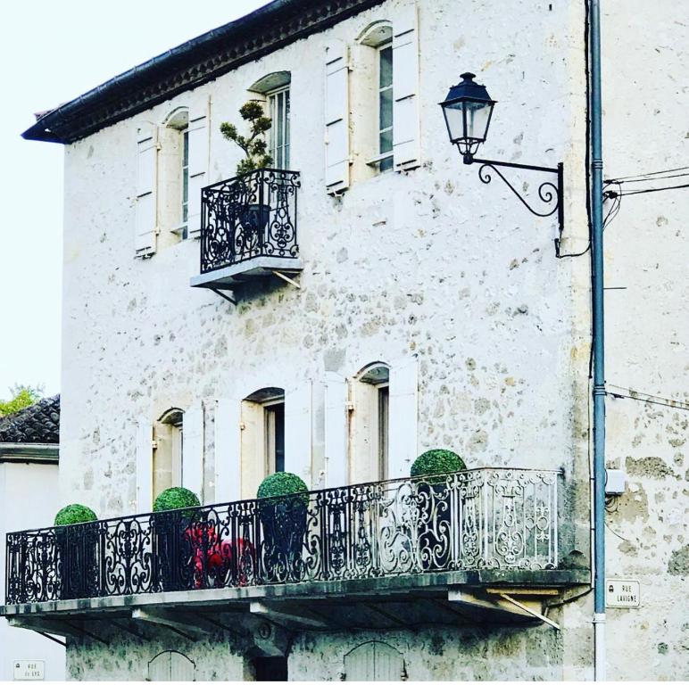 Un edificio blanco con un balcón y una farola. en Chambre D'hôtes Maison Avenue Mondenard, en Nérac