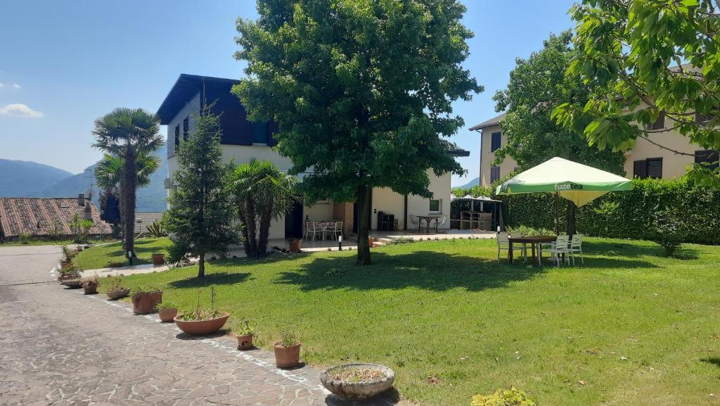 a garden with a table and a green umbrella at Villa Sara - Lake view, Garden & Private Parking in Lecco