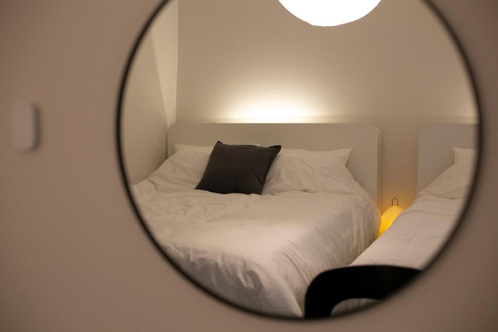 a mirror reflecting a bed with a black pillow at Staymuk Seochon, Center of Seoul in Seoul