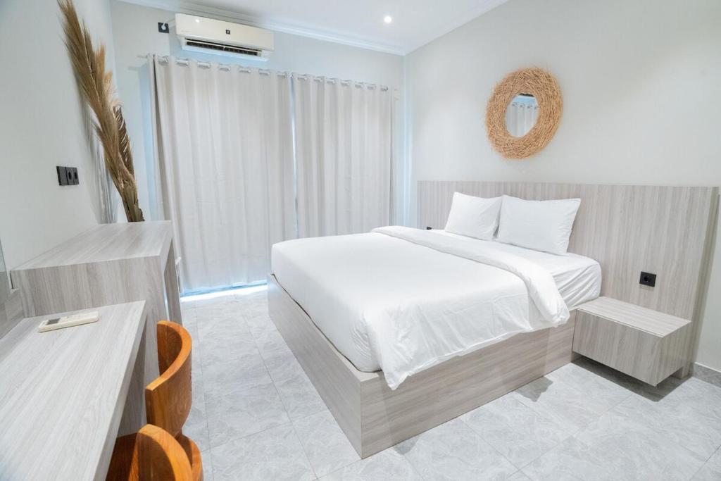 a white bedroom with a bed and a mirror at Villa Mentari at Umalas in Kerobokan