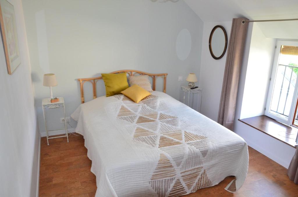 una camera da letto con un letto con lenzuola bianche e cuscini gialli di Chambre Pantagruel Le dolmen a Thizay