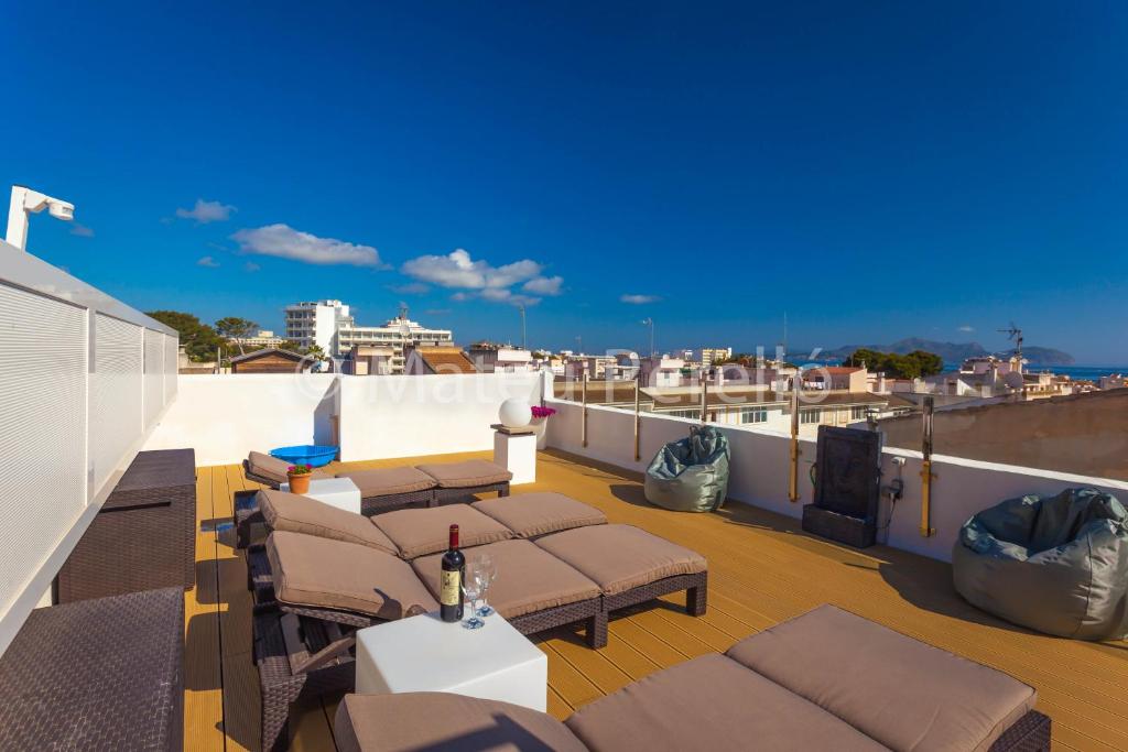 a rooftop deck with lounge chairs and a grill at Apartamentos Obelisc in Can Picafort