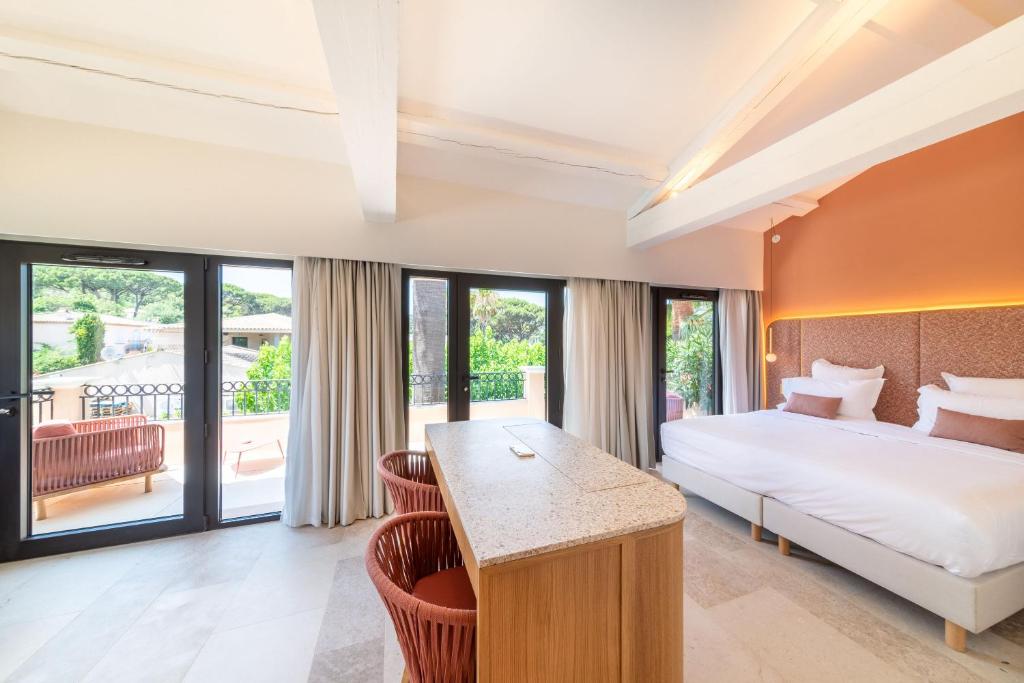 Hotel Brin d'Azur - Saint Tropez في سانت تروبيز: غرفة نوم بسرير ومكتب وبعض النوافذ