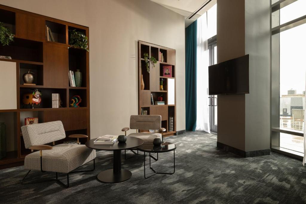 a living room with a table and chairs and a tv at The Cloud One New York-Downtown, by the Motel One Group in New York