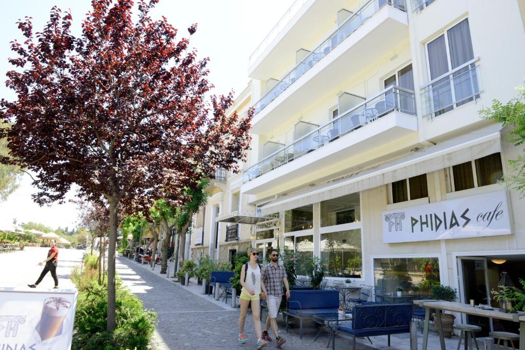 duas pessoas a andar numa rua em frente a um edifício em Phidias Hotel by Oniro em Atenas