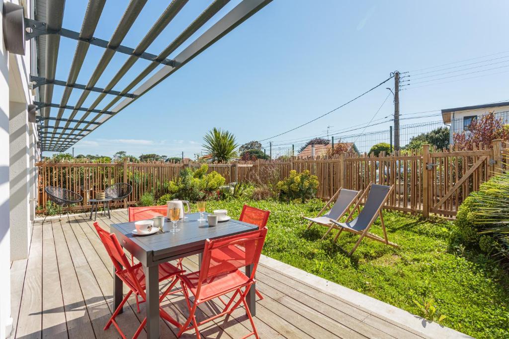a patio with a table and chairs on a deck at Bel appartement avec jardin proche des plages in Anglet