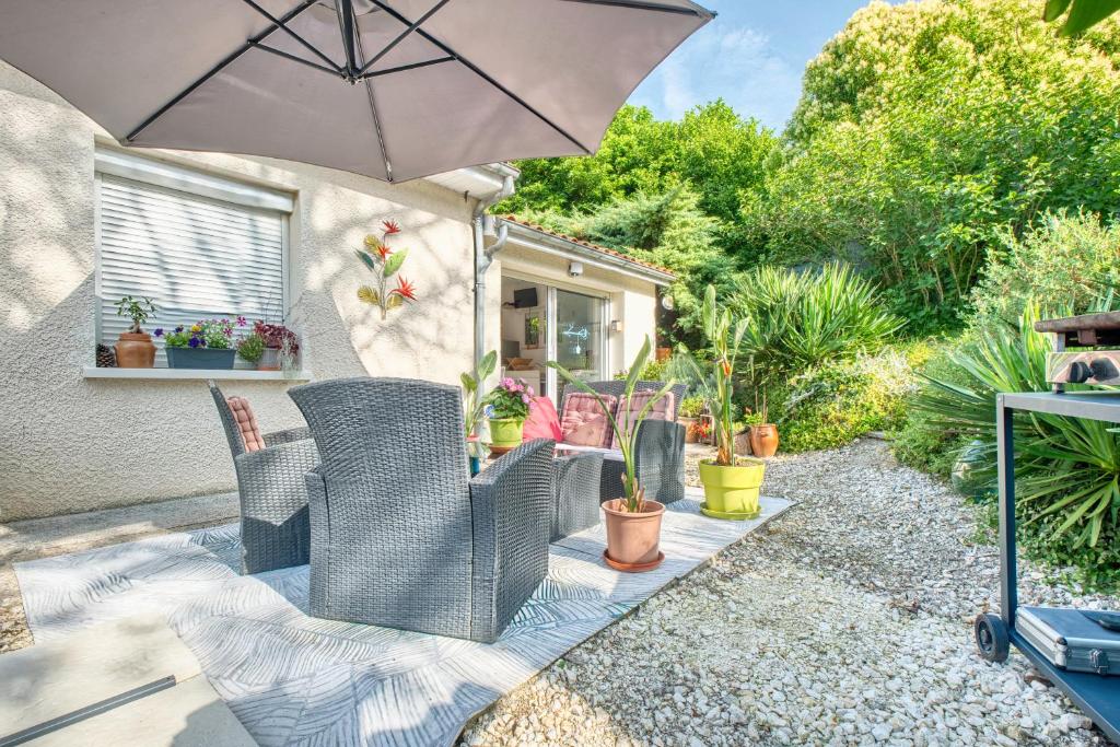 une terrasse avec des chaises, un parasol et des plantes dans l'établissement Gîte L'oiseau Du Paradis, à Ribérac