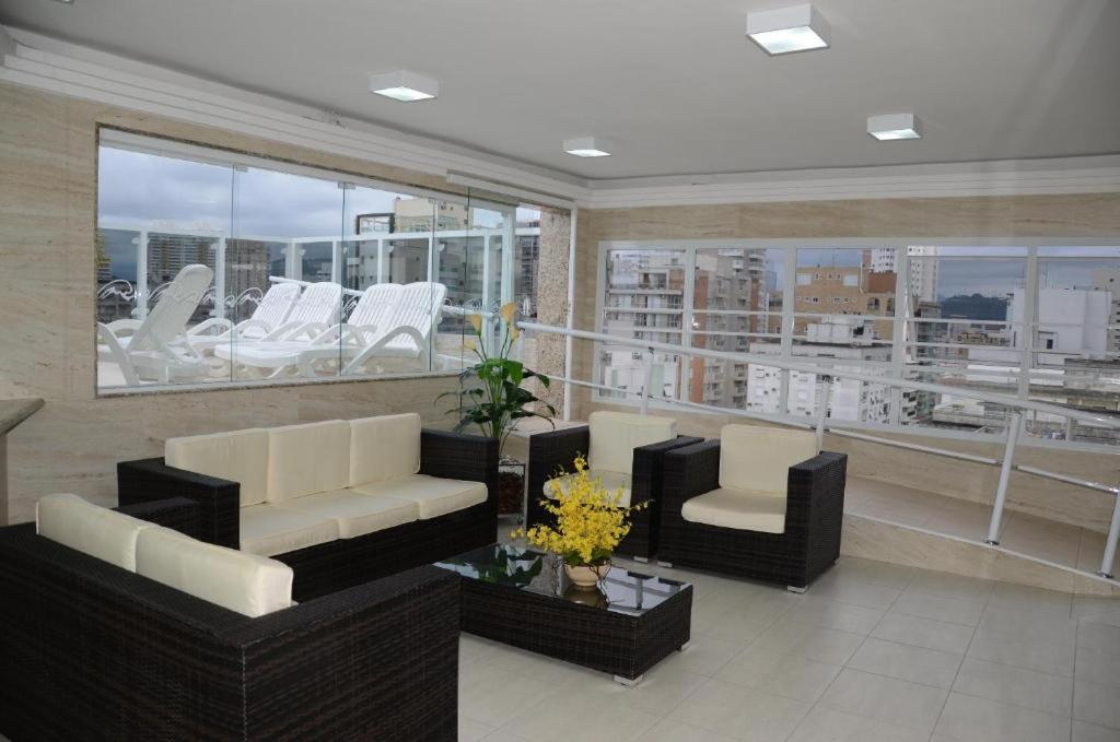 a living room with couches and chairs on a balcony at Gonzaga Praia Flat in Santos