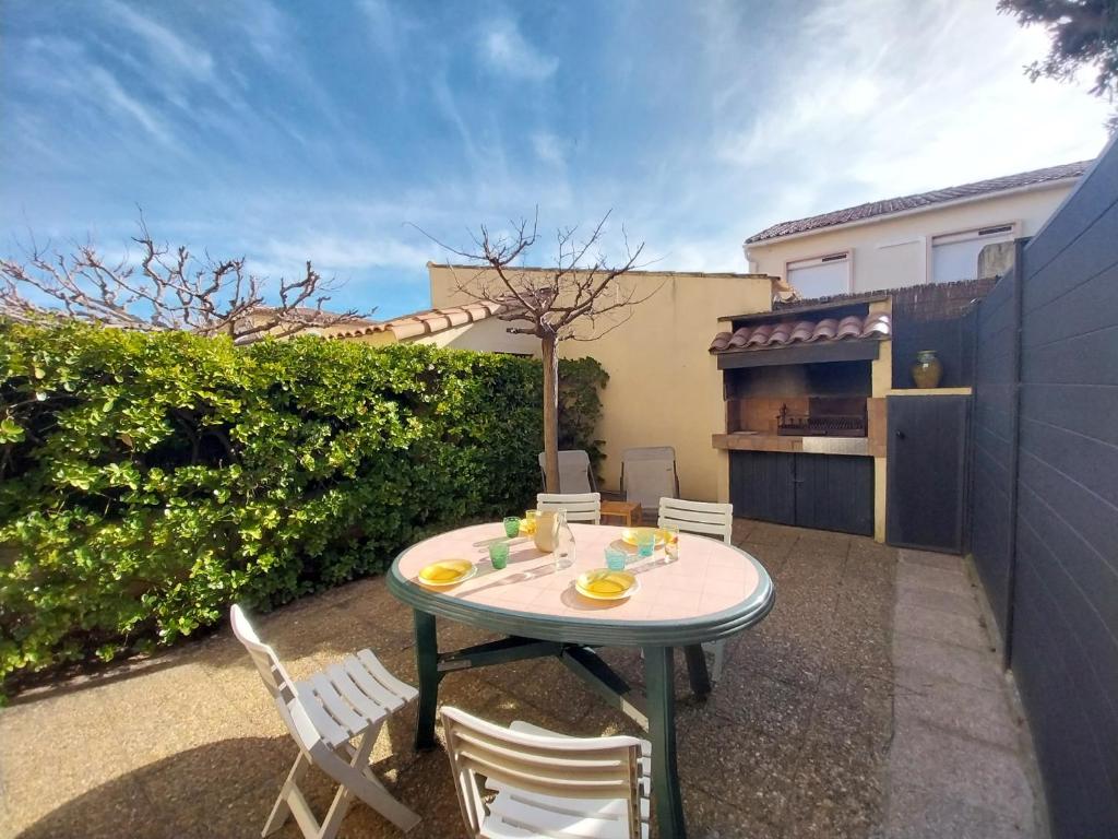 Un patio con mesa y sillas y un edificio. en DUPLEX T3 Terrasse proche mer, en Narbonne-Plage