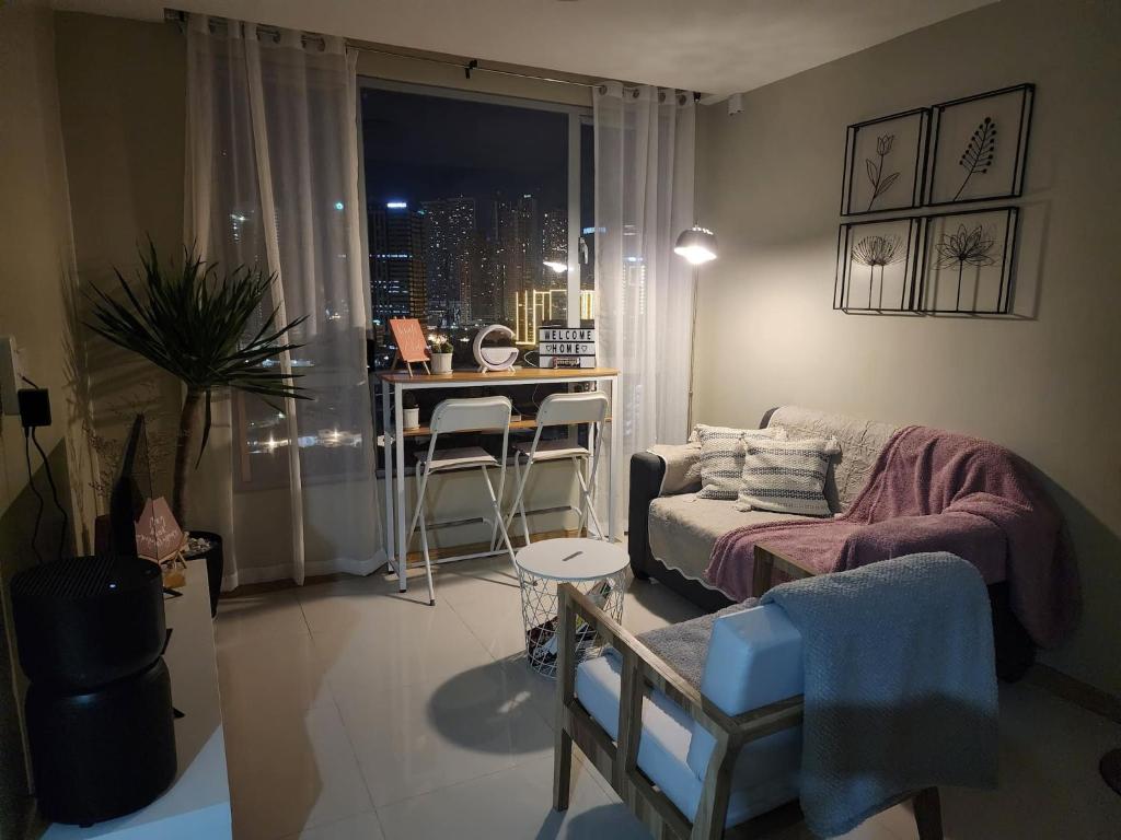 a living room with a couch and a table at Cozy 1BR Corner with Panoramic City Skyline View in Manila