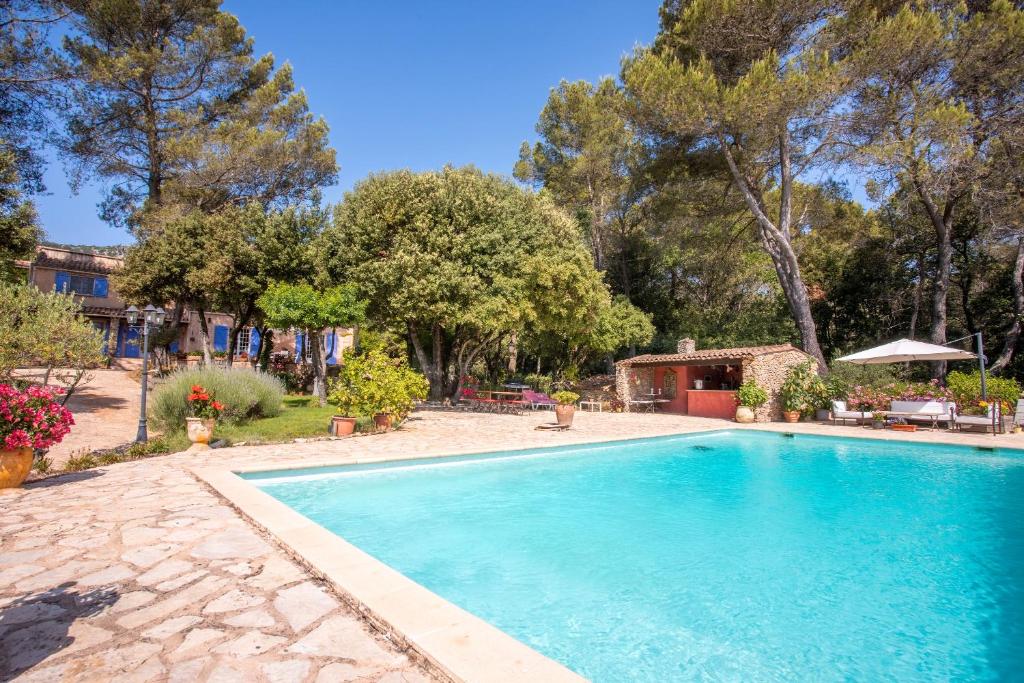 a large swimming pool in a yard with trees at Bastide Lou Pèbre D’aï in La Roquebrussanne