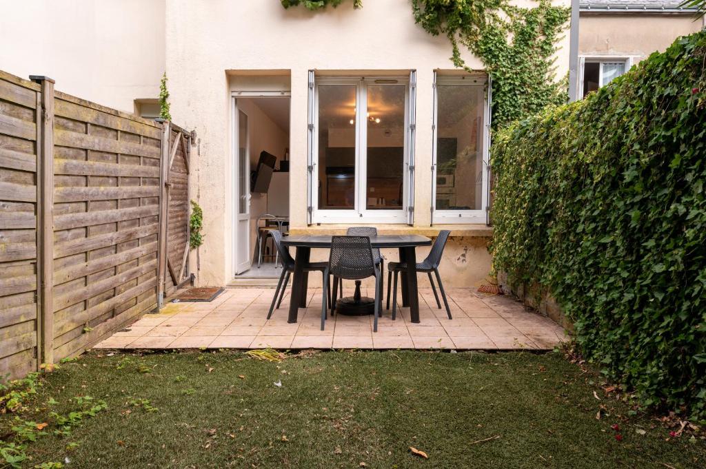 une terrasse avec une table et des chaises devant une clôture dans l'établissement Appartement Kerjulaude -Breizh key, à Lorient