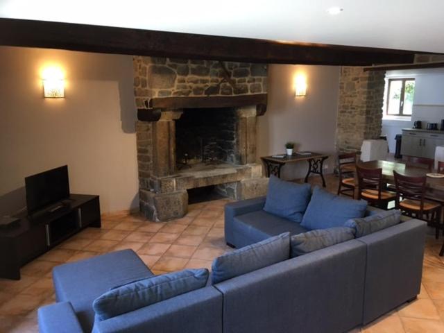 ein Wohnzimmer mit blauen Sofas und einem Steinkamin in der Unterkunft Gîte Aronde in Roz-sur-Couesnon