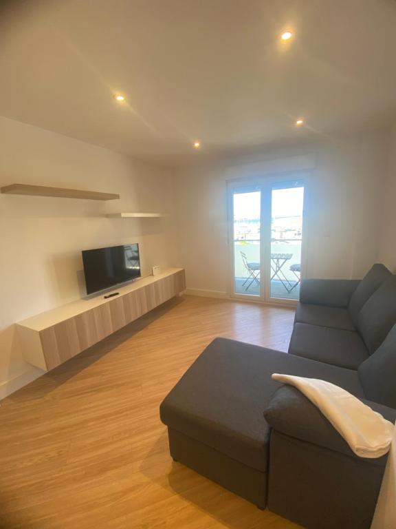 a living room with a couch and a flat screen tv at Apartamentos Mar de la Concha in Vilagarcia de Arousa