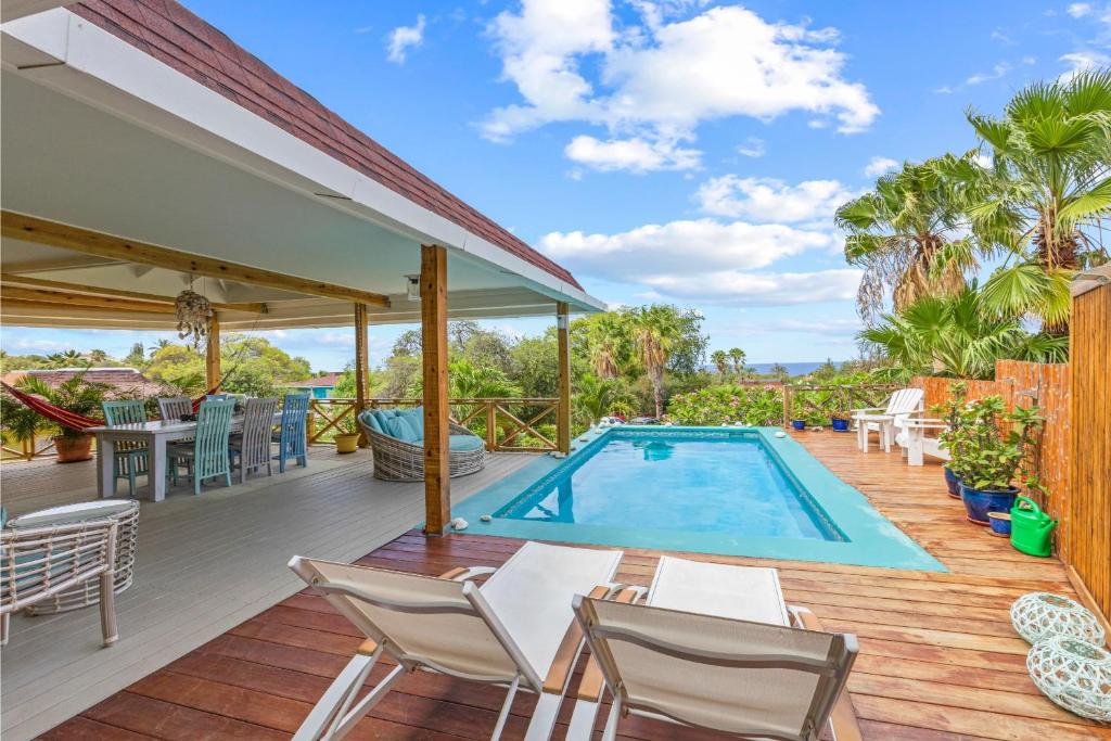 an outdoor deck with a swimming pool and chairs at Piscadera Bay Resort 18 in Willemstad