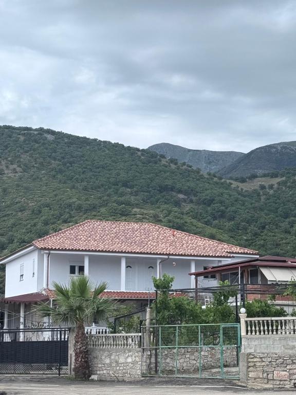 a white house with a fence and mountains in the background at Denaj House in Himare