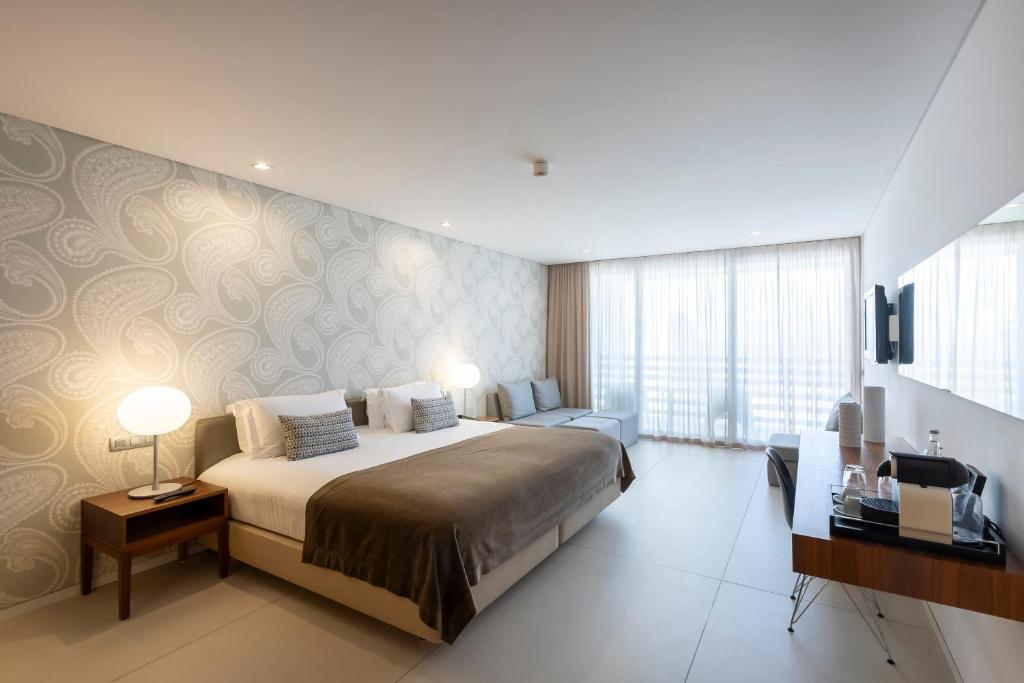 a bedroom with a large bed and a television in it at Troia Design Hotel in Troia